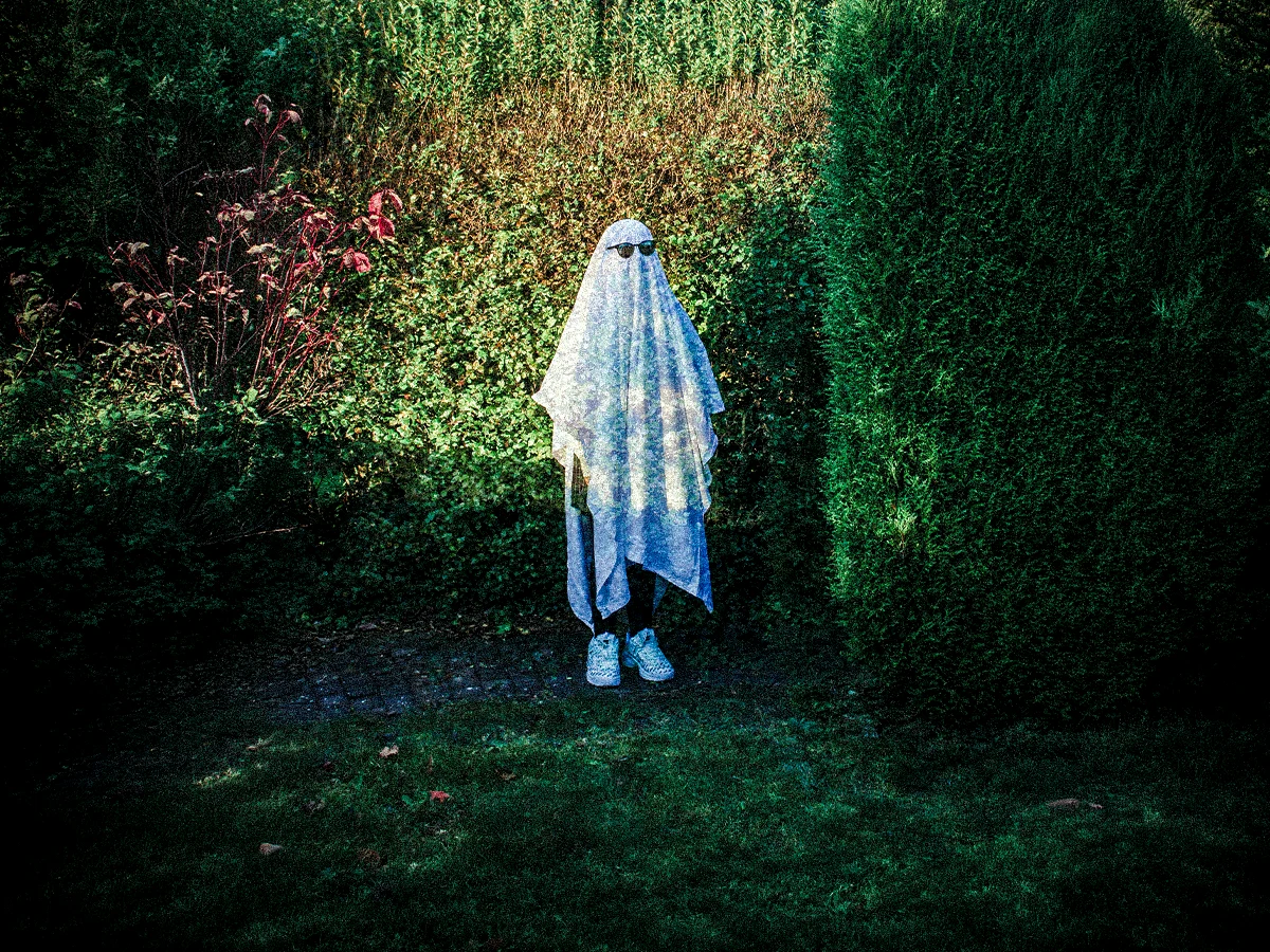A woman wearing a sheet like a ghost.